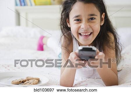 Stock Photo - Mixed race girl using remote control. Fotosearch