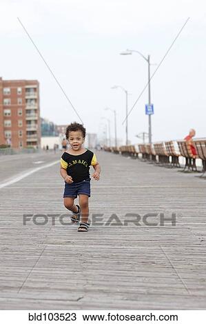 Stock Image - Mixed race girl walking on waterfront boardwalk. Fotosearch