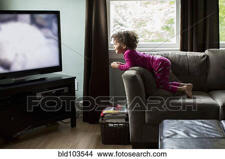 Picture - Mixed race girl watching television. Fotosearch