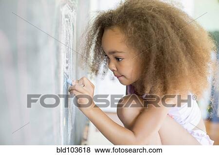 Stock Photo - Mixed race girl writing on blackboard. Fotosearch