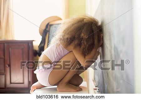 Stock Photograph - Mixed race girl writing on blackboard. Fotosearch