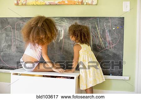 Stock Photo - Mixed race girls writing on blackboard. Fotosearch