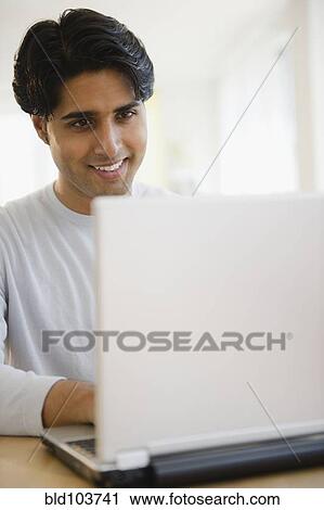 Stock Image - Mixed race man using laptop. Fotosearch