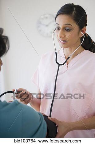 Mixed race nurse taking patient's blood pressure View Large Photo Image Picture - Mixed race nurse taking patient's blood pressure. Fotosearch