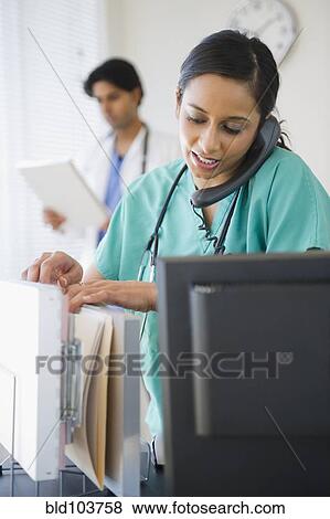 Stock Photo - Mixed race nurse talking on telephone. Fotosearch