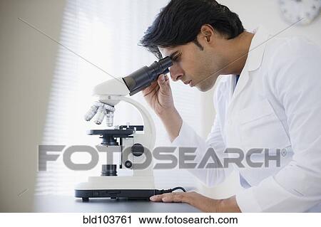 Stock Image - Mixed race scientist peering into microscope. Fotosearch