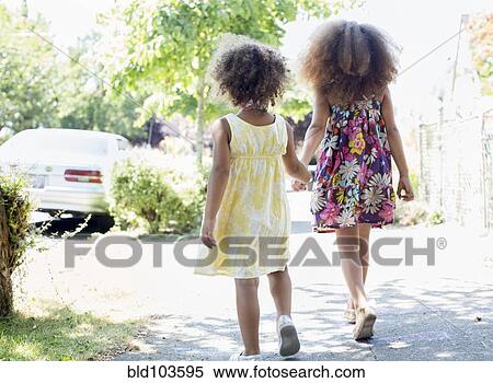 Stock Photography - Mixed race sisters holding hands. Fotosearch
