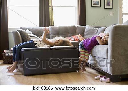 Stock Photography - Mixed race sisters in living room. Fotosearch