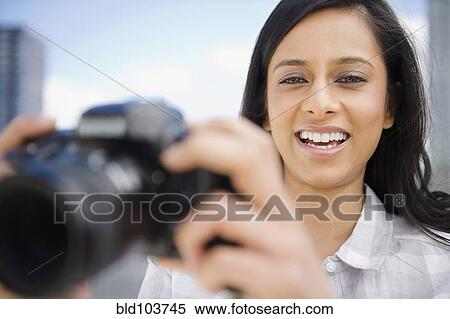 Stock Photography - Mixed race woman taking photographs. Fotosearch
