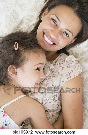 Mother and daughter laying on bed View Large Photo Image Stock Image - Mother and daughter laying on bed. Fotosearch