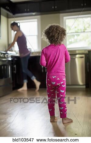 Stock Photo - Mother and daughter standing in kitchen. Fotosearch