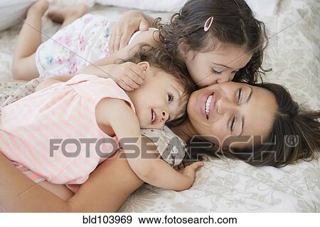 Mother and daughters laying on bed View Large Photo Image Stock Photo - Mother and daughters laying on bed. Fotosearch