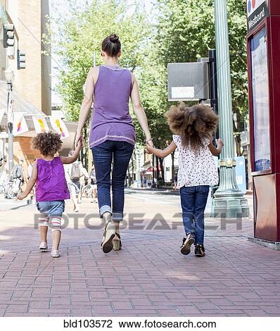 Mother and daughters walking on city street View Large Photo Image Stock Image - Mother and daughters walking on city street. Fotosearch