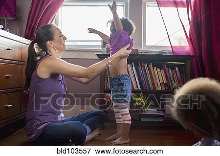 Stock Photo - Mother helping daughter get dressed. Fotosearch