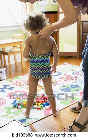 Stock Photo - Mother putting bathing suit on daughter. Fotosearch