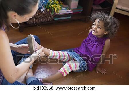 Mother putting shoes on daughter View Large Photo Image Stock Photo - Mother putting shoes on daughter. Fotosearch