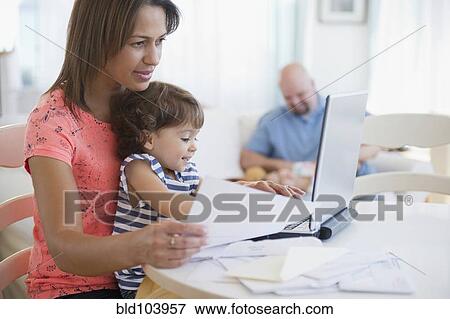 Mother working at computer with child on her lap View Large Photo Image Stock Photo - Mother working at computer with child on her lap. Fotosearch