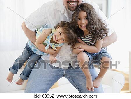 Stock Image - Playful father carrying daughters. Fotosearch