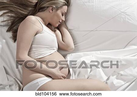 Stock Photograph - Pregnant woman sleeping in bed. Fotosearch