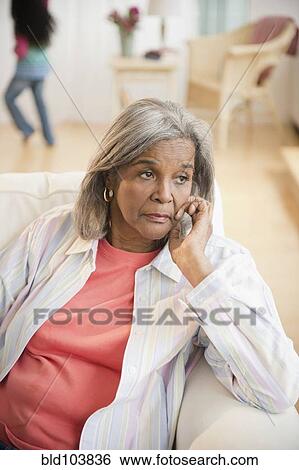 Serious African American woman sitting on sofa View Large Photo Image Stock Photograph - Serious African American woman sitting on sofa. Fotosearch