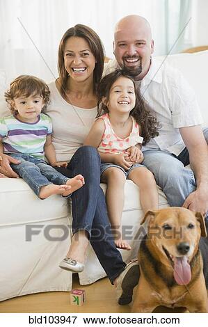Stock Photo - Smiling family sitting on sofa. Fotosearch