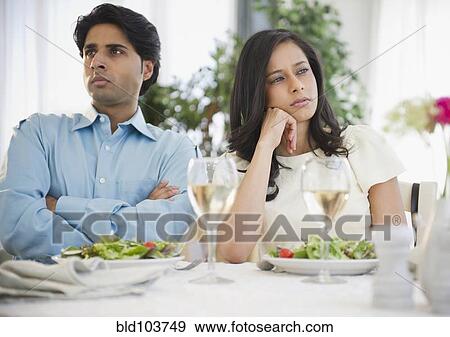 Stock Photo - Unhappy mixed race couple dining together. Fotosearch