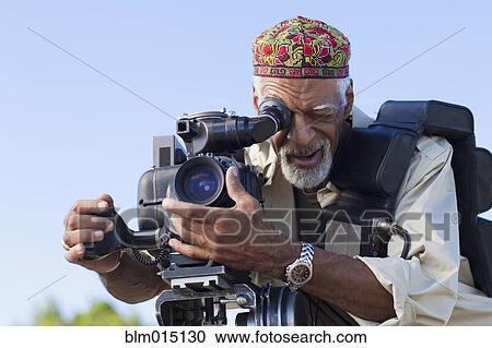 Stock Image - African American man using film camera. Fotosearch