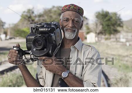 Stock Image - African American man using film camera. Fotosearch