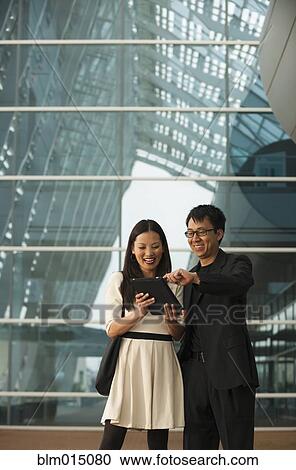 Stock Image - Asian business people using digital tablet. Fotosearch