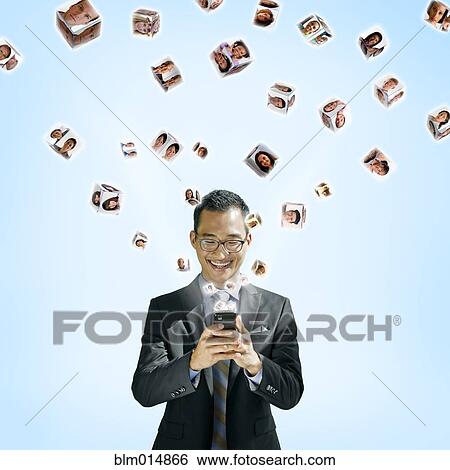 Stock Photograph - Asian businessman using cell phone with images floating above. Fotosearch