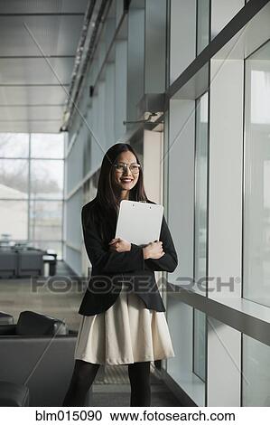 Stock Image - Asian businesswoman holding clipboard. Fotosearch