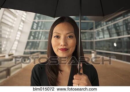 Stock Image - Asian businesswoman underneath umbrella. Fotosearch