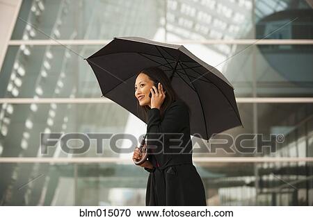 Asian businesswoman with umbrella talking on cell phone View Large Photo Image Stock Image - Asian businesswoman with umbrella talking on cell phone. Fotosearch