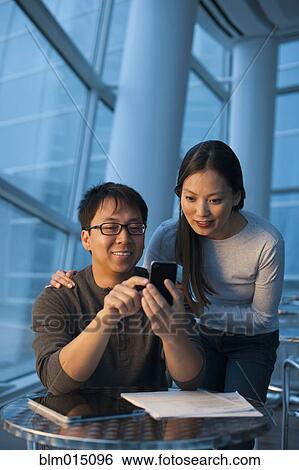 Asian couple looking at cell phone View Large Photo Image Stock Photograph - Asian couple looking at cell phone. Fotosearch