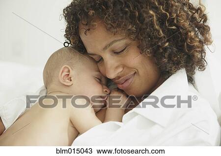 Stock Image - Black mother laying with baby. Fotosearch