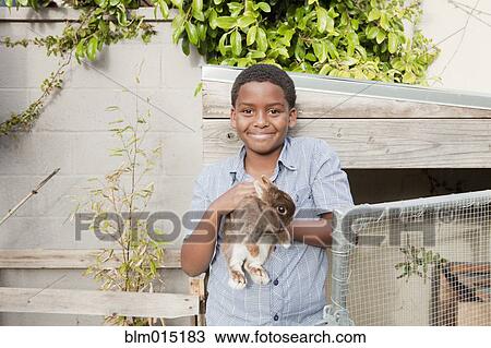 Stock Image - Boy holding rabbit. Fotosearch