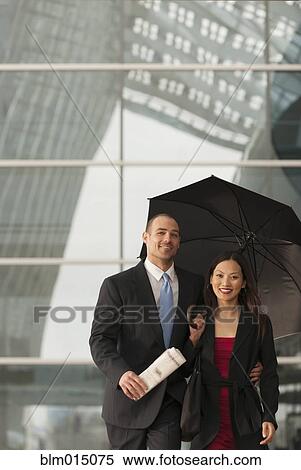 Stock Photography - Business people standing together with umbrella. Fotosearch