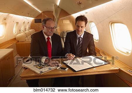 Stock Image - Caucasian businessmen working on private jet. Fotosearch