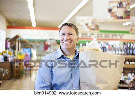 Caucasian man carrying bag in grocery store View Large Photo Image Stock Image - Caucasian man carrying bag in grocery store. Fotosearch