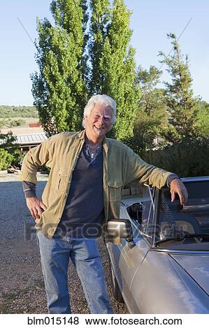 Stock Photo - Caucasian man leaning on convertible. Fotosearch