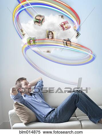 Stock Photography - Caucasian man looking at colorful lines and images above his head. Fotosearch