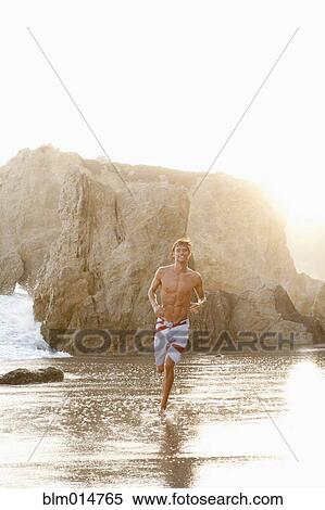 Stock Photography - Caucasian man running on beach. Fotosearch