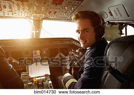 Stock Image - Caucasian pilot flying jet at sunset. Fotosearch
