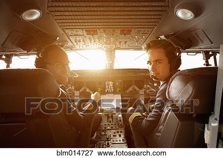 Stock Photo - Caucasian pilots flying jet at sunset. Fotosearch