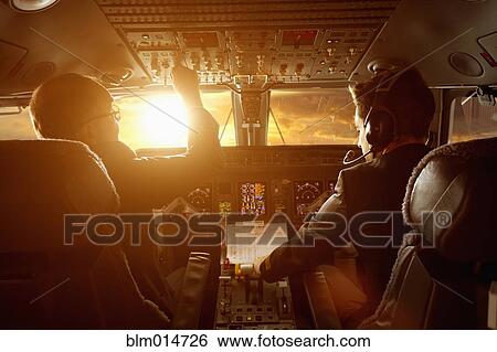 Stock Photograph - Caucasian pilots flying jet at sunset. Fotosearch