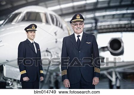 Caucasian pilots standing with airplane in hangar View Large Photo Image Stock Photo - Caucasian pilots standing with airplane in hangar. Fotosearch