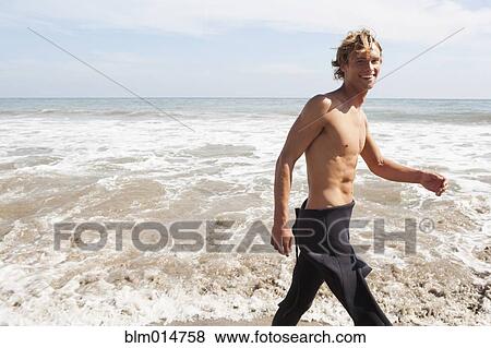Stock Photo - Caucasian surfer walking on beach. Fotosearch