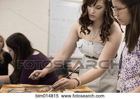 Stock Photography - Caucasian teacher helping student in art class. Fotosearch