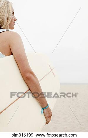 Caucasian woman carrying surfboard View Large Photo Image Stock Photo - Caucasian woman carrying surfboard. Fotosearch