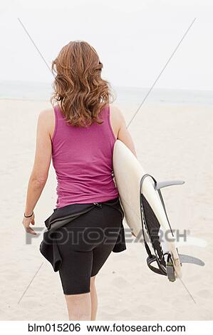 Stock Photograph - Caucasian woman carrying surfboard. Fotosearch